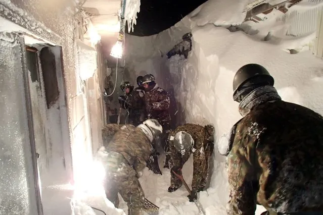 This handout picture taken by Rausu town government on February 2, 2015 shows members of Japan's ground self defense force removing snow from the entrance of a house at Rausu town in Japan's northern island of Hokkaido. Parts of northern Japan were digging out from nearly six feet (1.8 metres) of snow after a massive winter storm dumped record amounts. (Photo by AFP Photo)