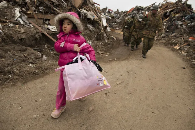Neena Sasaki, 5, carries some of the family belongings from her home that was destroyed after the devastating earthquake and tsunami on March 15, 2011 in Rikuzentakata,  Miyagi province, Japan. Thousands have been killed after the 8.9 earthquake struck the northeast coast of Japan 4 days ago. Presently the country is struggling to contain a potential nuclear meltdown after the Fukushima Daiichi nuclear plant was seriously damaged from the earthquake. (Photo by Paula Bronstein /Getty Images)