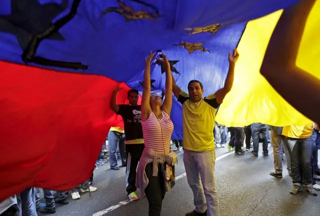Supporters of Venezuela's opposition carry a giant national flag some streets away from the building housing the National Assembly in Caracas, January 5, 2016. (Photo by Marco Bello/Reuters)