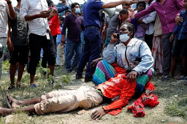 A man holds a mourner who fainted at the site where several people died as a ferry collided with a cargo vessel and sank on Sunday in the Shitalakhsyaa River in Narayanganj, Bangladesh, April 5, 2021. (Photo by Mohammad Ponir Hossain/Reuters)