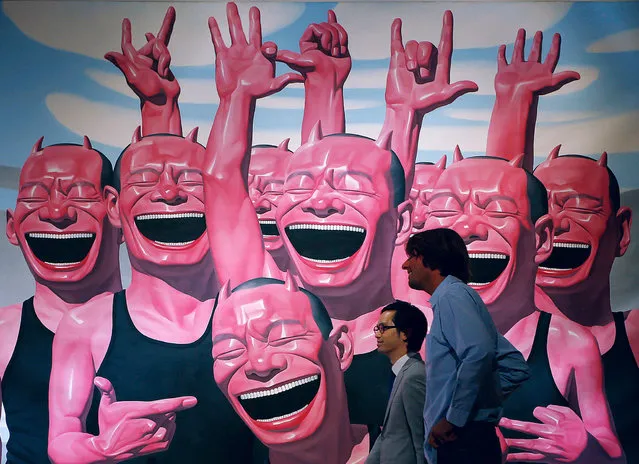 Two men walk past a painting by Chinese artist Yue Minjun titled “Between Men and Animal”  during a press preview for a Sotheby's auction in Hong Kong, Wednesday, October 2, 2013. The work is estimated at US$644,650 to 1,031,440 and will be auctioned as part of the autumn sale from October 4–8. (Photo by Vincent Yu/AP Photo)