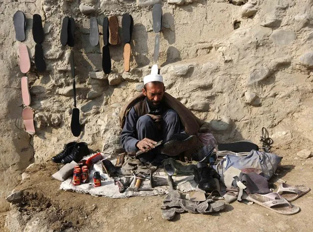 A cobbler sits at a roadside as he brushes a customer's shoes in Kabul, January 26, 2015. (Photo by Omar Sobhani/Reuters)