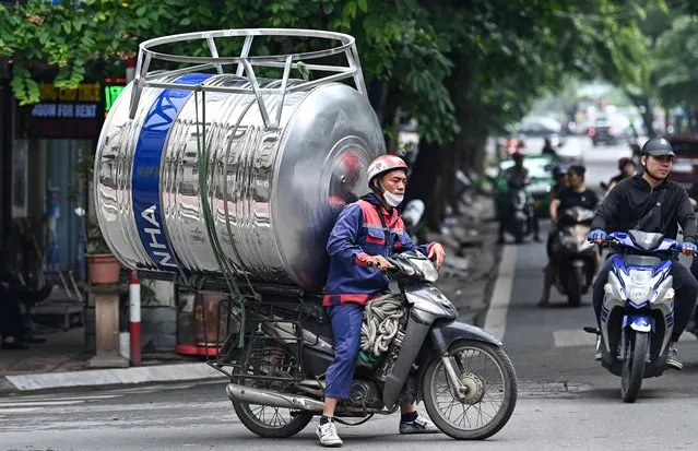 A worker transports a water tank on his motorbike in Hanoi on June 21, 2023. (Photo by Nhac Nguyen/AFP Photo)