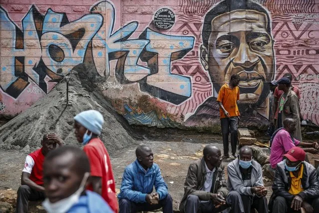 Local residents sit next to a mural painted in June 2020 showing George Floyd with the Swahili word “Haki” or “Justice” in the Kibera low-income neighborhood of Nairobi, Kenya, Wednesday, April 21, 2021. After three weeks of testimony, the trial of the former police officer charged with killing George Floyd ended swiftly: barely over a day of jury deliberations, then just minutes for the verdicts to be read – guilty, guilty and guilty – and Derek Chauvin was handcuffed and taken away to prison. The guilty verdict in the George Floyd trial was not just America's victory. It signaled hope for those seeking racial justice and fighting police brutality across the Atlantic. (Photo by Brian Inganga/AP Photo)