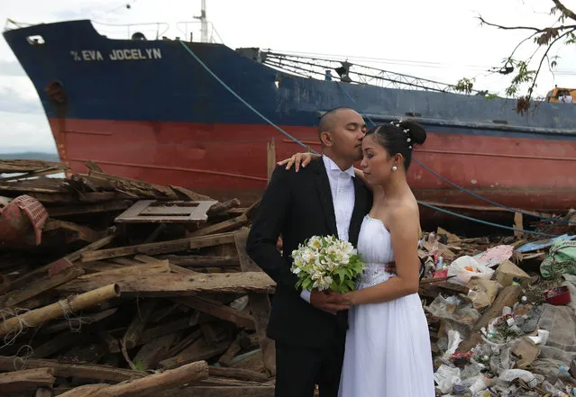 In this December 7, 2013, file photo, Filipino groom Earvin Nierva, left, kisses his bride Riza as they pose for their wedding pictures taken by a photographer beside damaged homes and a ship that was washed ashore when Typhoon Haiyan hit Tacloban city, central Philippines. The newly-wed couple decided to have the photo shoot at the area to symbolize that they can overcome tragedy and to urge residents to “stand up and rise again”. Filipinos are facing the powerful Typhoon Mangkhut with the memory of another devastating storm still fresh in their minds. Nearly five years ago, Typhoon Haiyan left more than 7,300 people dead or missing, flattened entire villages, swept ships inland and displaced more than 5 million in the central Philippines, well to the south of Mangkhut’s path. (Photo by Aaron Favila/AP Photo)