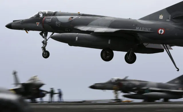 In this Tuesday, March 17, 2015 photo, a French military plane lands on the flight deck of the French Navy aircraft carrier Charles de Gaulle, in the Persian Gulf. (Photo by Hasan Jamali/AP Photo)