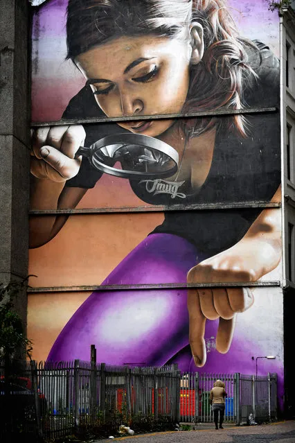 A woman walks past one of the murals in Mitchel Lane on October 26, 2016 in Glasgow, Scotland. The murals have been appearing across the city for a since 2008 with new ones appearing on a regular bases rejuvenating bare walls revitalising tired corners of Glasgow. Now a new Mural Trail has been devised with a huge range of them on display within a short walking distance from the city centre. (Photo by Jeff J. Mitchell/Getty Images)