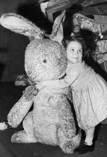 Pamela Offor develops a deep affection for this giant toy rabbit, one of the many toys that were sent to British children in London by the Belgians, December 13, 1944. Belgium has offered to send gifts of toys for British children, and these marked the arrival of the first shipment. (Photo by AP Photo)