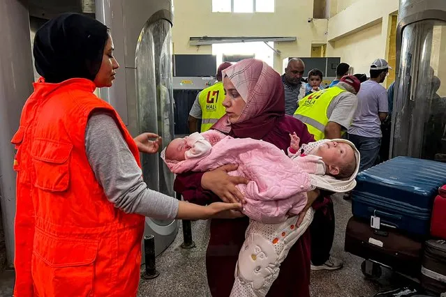 A woman walks with two infants after crossing on the Egyptian side of the Rafah border crossing with the Gaza Strip in the northeastern North Sinai province on November 6, 2023, amid ongoing battles between Israel and the Palestinian Hamas movement. (Photo by AFP Photo/Stringer)