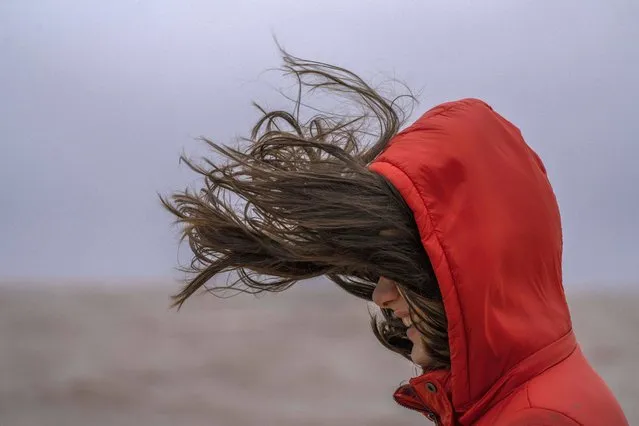 A person walks on the sea wall as a Southeast wind blows in Montevideo, Uruguay on Sunday, July 18, 2021. (Photo by Matilde Campodonico/AP Photo)