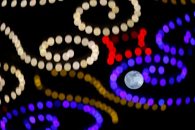 The rising full moon is seen behind Christmas lights in Valletta, Malta on December 23, 2018. (Photo by Darrin Zammit Lupi/Reuters)