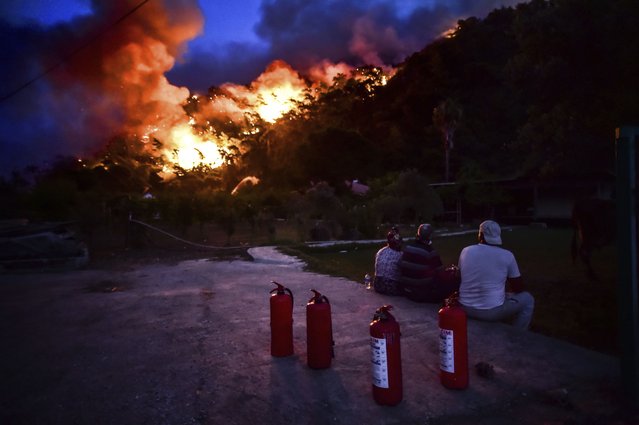 People watch before they leave as advancing fires rage Hisaronu area, Turkey, Monday, August 2, 2021. (Photo by AP Photo/Stringer)