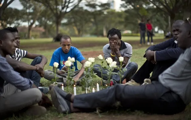 A group of students and other Kenyans sit around white roses and candles and discuss the recent attack in Garissa, as they wait for a vigil at Uhuru Park in Nairobi, Kenya Tuesday, April 7, 2015. (Photo by Ben Curtis/AP Photo)