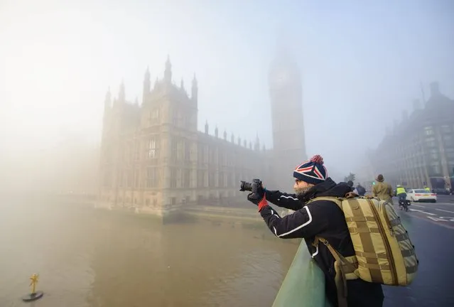 A man videos the Houses of Parliament in thick fog from Westminster Bridge, in Westminster, central London, on December 11, 2013. (Photo by Dominic Lipinski/PA Wire)