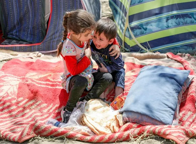 An internally displaced boy from northern provinces, who fled from his home due the fighting between Taliban and Afghan security forces, is comforted by his sister in a public park that they use as shelter in Kabul, Afghanistan, August 10, 2021. (Photo by Reuters/Stringer)