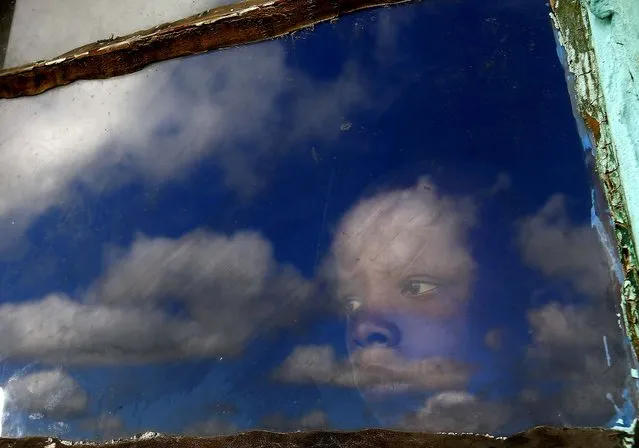 A boy looks out from his hut's window at the burial ground of late former South African President Nelson Mandela ahead of his funeral in Qunu, on December 15, 2013. (Photo by Yannis Behrakis/Reuters)
