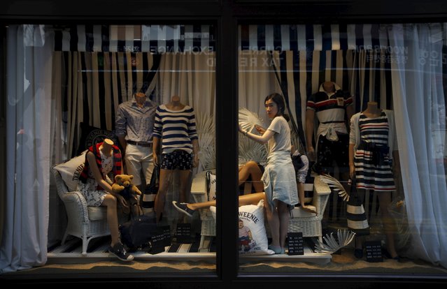 A shop assistant arranges summer clothes in a shop window in the Myeong-dong shopping district in Seoul in this May 20, 2014 file photo. South Korea is expected to release inflation data this week. (Photo by Kim Hong-Ji/Reuters)