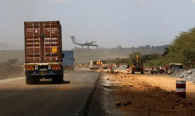 A plane flies over traffic along the Southern bypass road under construction next to the Nairobi National Park in Kenya's capital Nairobi, March 4, 2016. Kenya Wildlife Service (KWS) and the Ministry of Transport agreed to cut off about 53 acres of land from the Nairobi National Park to allow for completion of the 28 kms Nairobi Southern bypass road project. (Photo by Thomas Mukoya/Reuters)