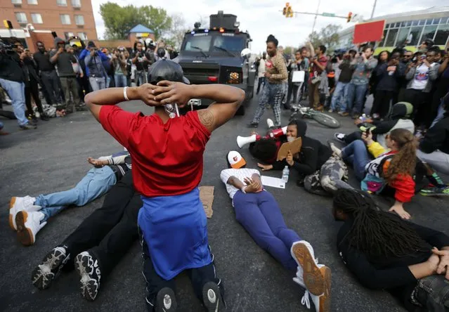 Members of the community lie down in the street, forcing a police armored vehicle to reverse back down the street in Baltimore, Maryland, April 28, 2015. (Photo by Jim Bourg/Reuters)
