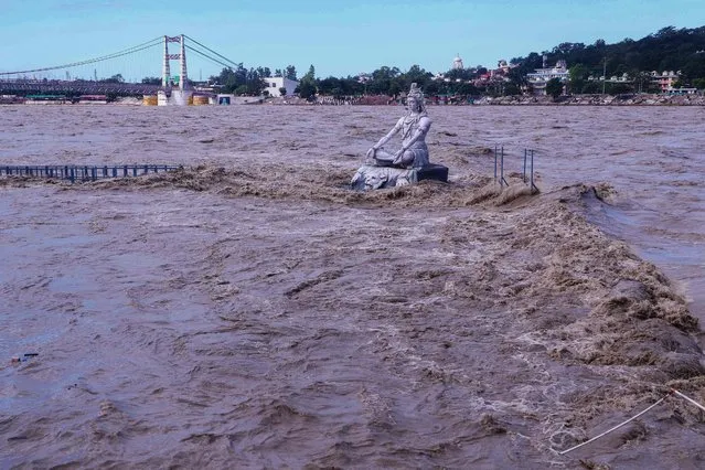 A statue of Hindu god Lord Shiva is pictured amid the risen water levels of River Ganga after incessant rains in Rishikesh in India's Uttrakhand state on October 19, 2021. (Photo by AFP Photo/Stringer Network)