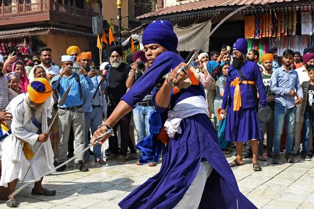 A Nihang or Sikh warrior performs “Gatka”, an ancient form of Sikh martial arts, during a religious procession on the eve of the birth anniversary of the fourth Sikh Guru Ram Das outside the Golden Temple in Amritsar on October 21, 2021. (Photo by Narinder Nanu/AFP Photo)