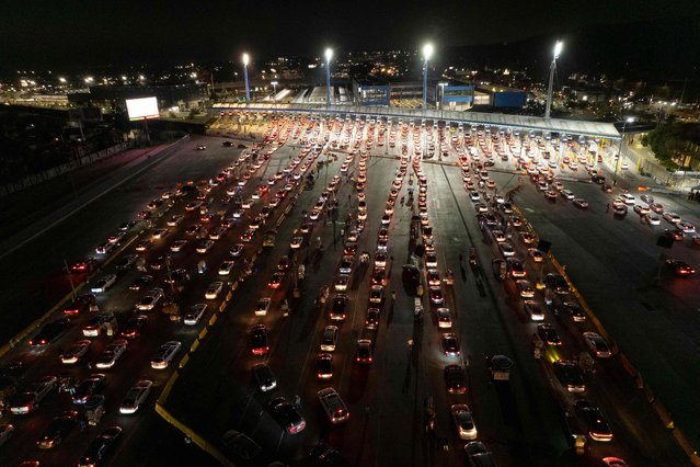 Aerial view of cars lining-up to cross the border at San Ysidro crossing port on the Mexico-United States border in Tijuana, Baja California state, Mexico, on November 7, 2021. On Monday 8, Washington will reopen its land borders with Mexico and Canada to foreigners vaccinated against Covid-19, almost 20 months after they were closed to non-essential traffic. (Photo by Guillermo Arias/AFP Photo)