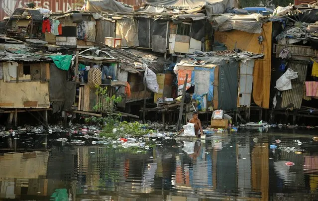 A man on a makeshift raft searches for discarded plastic bottles over a polluted river in Manila on March 22, 2016. Coal plants are draining an already dwindling global water supply, Greenpeace warned March 22, consuming enough to meet the basic needs of one billion people and deepening a worldwide crisis. (Photo by Noel Celis/AFP Photo)