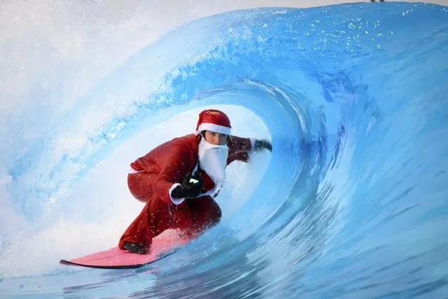 A surfer dressed as a Santa Claus rides an artificial wave in the Alaia Bay surf wavepool in Sion, Switzerland, 15 December 2021. The water temperature was 0.6 degrees Celsius, the air temperature reached two degrees Celsius. (Photo by Laurent Gillieron/EPA/EFE)