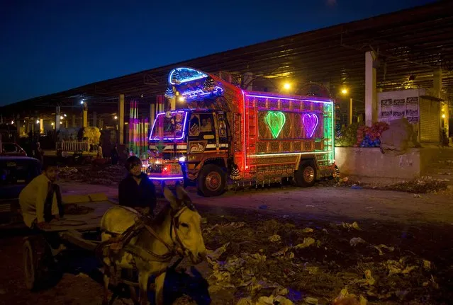 A truck decorated with florescent lights offloads vegetables and fruits at a wholesale market in Islamabad, Pakistan, on Wednesday, March 19, 2014. Owners of such trucks spend much money on decorating their vehicles in Pakistan. (Photo by B. K. Banagsh/AP Photo)