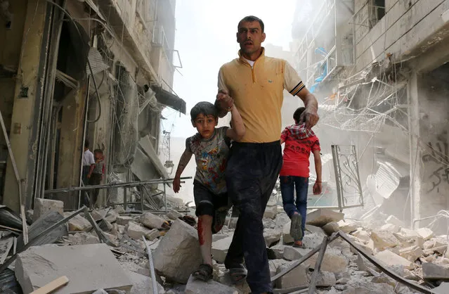 A Syrian man evacuates an area following a reported airstrike on April 22, 2016 in the rebel-held neighbourhood of Hayy Aqyul in Syria's second city Aleppo. Air strikes on rebel-held neighbourhoods in Syria's second city Aleppo killed at least 14 civilians and wounded more than a dozen others, the local civil defence told AFP. The Syrian Observatory for Human Rights said regime warplanes carried out the air strikes and gave a toll of 10 dead. (Photo by Ameer Alhalbi/AFP Photo)