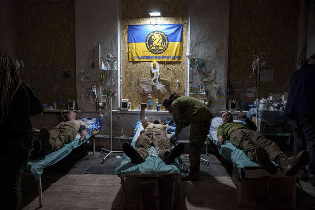A Ukrainian military medic of the 47th Brigade treats his injured comrades at the field hospital in Avdiivka direction, Donetsk region, Ukraine, Friday, May 10, 2024. (Photo by Evgeniy Maloletka/AP Photo)