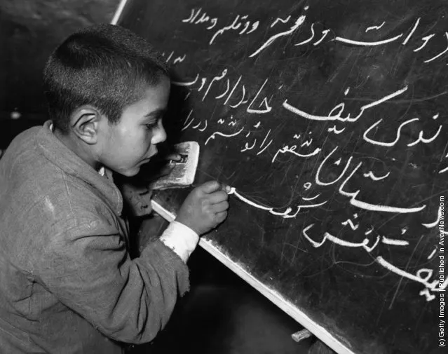 1950:  A young Iranian boy learning how to write on a blackboard