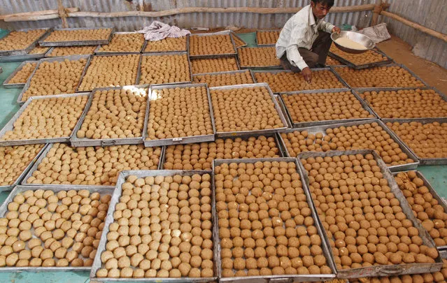 A worker arranges Laddus (sweets) at a temporarily built kitchen in Ahmedabad February 25, 2012. (Photo by Amit Dave/Reuters)
