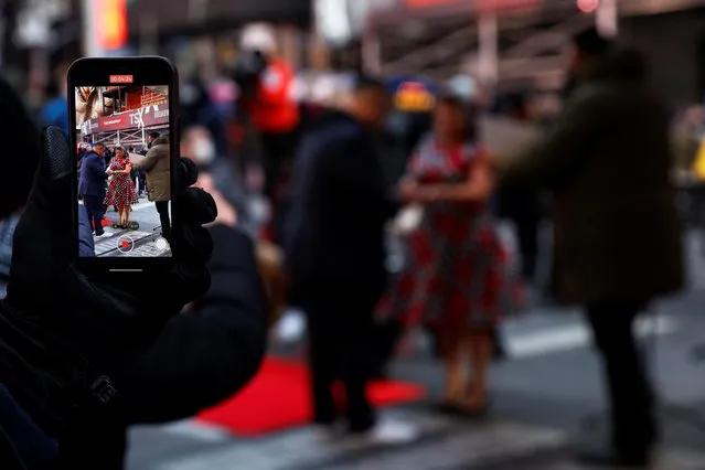 A person takes a video of a couple getting married during a ceremony at Times Square in New York City, U.S., February 14, 2022. (Photo by Shannon Stapleton/Reuters)