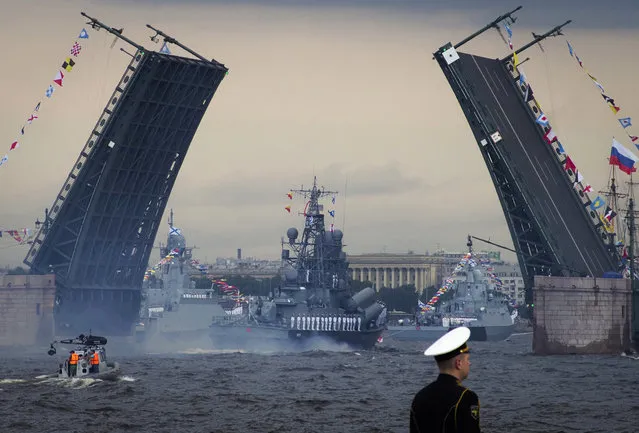 Warships float past the Dvortsovy (Palace) drawbridge rising above the Neva River during the Navy Day parade in St.Petersburg, Russia, Sunday, July 28, 2019. (Photo by Dmitri Lovetsky/AP Photo)