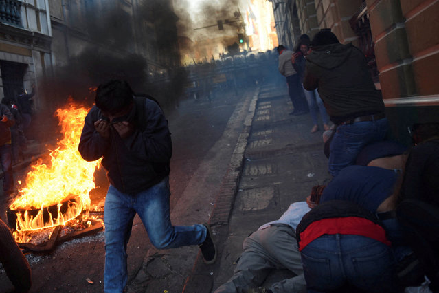 People cover their faces while demonstrators face members of Bolivia's military, as Bolivia's President Luis Arce “denounced the irregular mobilization” of some units of the country's army, in La Paz, Bolivia, on June 26, 2024. (Photo by Claudia Morales/Reuters)