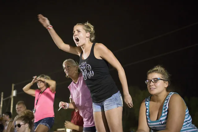 In this July 17, 2015 photo, Sara Henry cheers for her husband during dirt track racing at the Ponderosa Speedway in Junction City, Ky. Jake Henry finished in third place in his division in the final race. (Photo by David Stephenson/AP Photo)