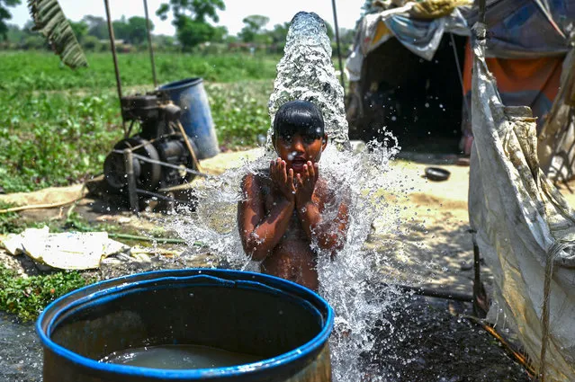 A boy cools himself off at a tubewell near a field amid rising temperatures in New Delhi on April 6, 2022. (Photo by Money Sharma/AFP Photo)