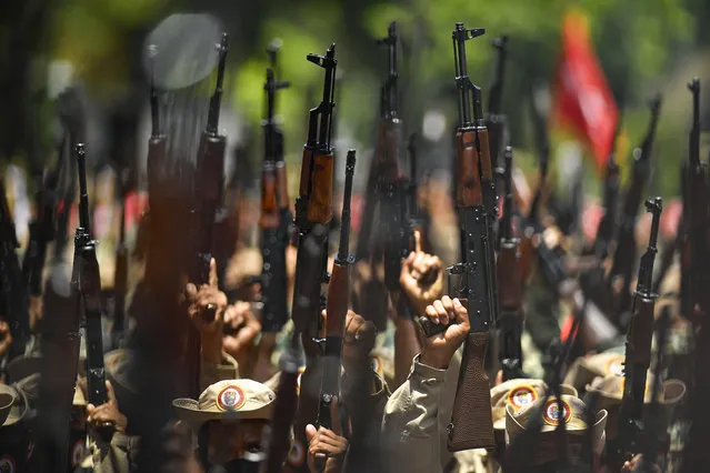 Members of the Venezuelan National Bolivarian Militia, a branch of the National Armed Forces created by the late President Hugo Chavez, raise their weapons during the celebration of the militia´s 13th anniversary, in Caracas, Venezuela, Wednesday, April 13, 2022. Government supporters are also commemorating the 20th anniversary of Chavez's return to power after a failed coup in 2002. (Photo by Matias Delacroix/AP Photo)