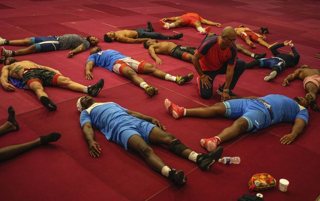 Members of the Cuban national Greco-Roman wrestler team stretch out on the mat during a training session in Varadero, Cuba, Wednesday, April 3, 2024.  Teammate Mijain Lopez Nunez is part of the Cuban delegation headed to Paris in pursuit of a fifth Olympic gold to mark the end of his career. (Photo by Ramon Espinosa/AP Photo)