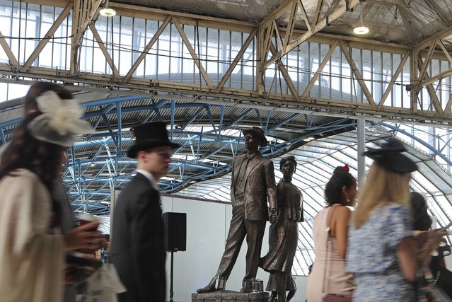 People bound for Royal Ascot race meeting walk past the National Windrush Monument in Waterloo Station in London, Thursday June 22, 2023. Windrush Day is being marked on Thursday on what is the 75th anniversary of the arrival of the ship the Empire Windrush on June 22, 1948. It became a symbol of the post-war migration that transformed the U.K. and its culture. The term Windrush generation has come to stand for hundreds of thousands of people who arrived in the U.K. between the late 1940s and early 1970s, especially those from former British colonies in the Caribbean. (Photo by Tony Hicks/AP Photo)