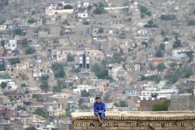 A child sits on the roof of his house in Kabul, Afghanistan, Friday, April 22, 2022. (Photo by Ebrahim Noroozi/AP Photo)