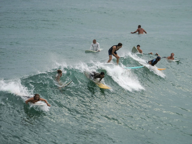 Surfers catch a wave in Navarre Beach, Fla., Sunday, June 16, 2024. (Photo by Kiichiro Sato/AP Photo)