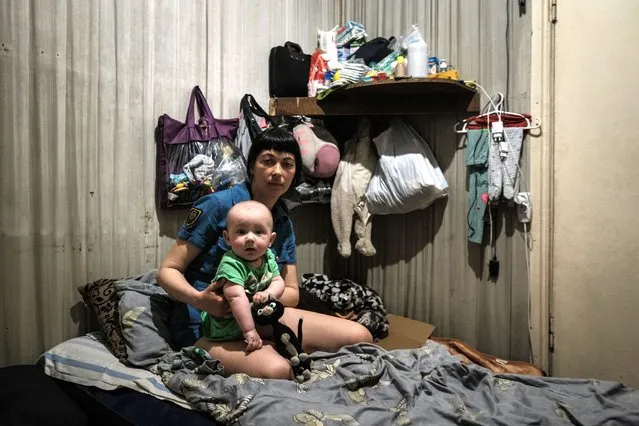 Kateryna, 33-year-old, poses with her 7-month-old daughter in the bunker of a closed glass factory in Lysychansk, eastern Ukraine, on April 27, 2022, amid the Russian invasion of Ukraine. (Photo by Yasuyoshi Chiba/AFP Photo)