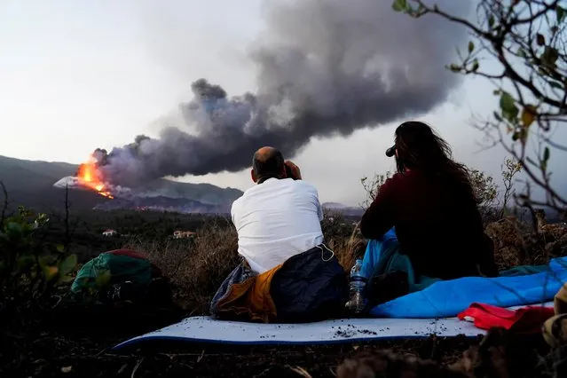 A couple watches as the Cumbre Vieja volcano continues to erupt, from Tacande de Arriba, Spain, October 2, 2021. (Photo by Juan Medina/Reuters)