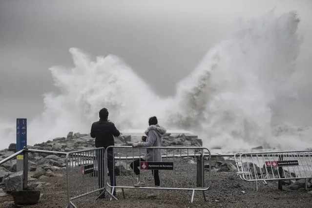Two people watch the waves hitting the breakwater in Barcelona, Spain, Wednesday, January 22, 2020. Massive waves and gale-force winds smashed into seafront towns, damaging many shops and restaurants and flooding some streets. (Photo by Joan Mateu/AP Photo)
