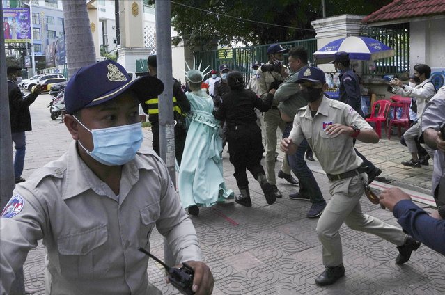 Cambodian-American lawyer Theary Seng, rear center, dressed in the Lady Liberty, is escorted by local police officers outside Phnom Penh Municipal Court in Phnom Penh, Cambodia, Tuesday, June 14, 2022. The Cambodian American lawyer and dozens of other members of a now-dissolved opposition party awaited a verdict Tuesday in their trial for treason that marked the latest move to tame all opposition to the long-running rule of Prime Minister Hun Sen. (Photo by Heng Sinith/AP Photo)