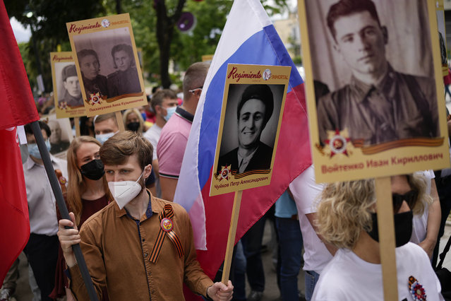 Russian nationals hold posters depicting family members who were killed in WWII during an Immortal Regiment march to commemorate those who fought and died during that war and the victory over Nazism, at Los Proceres Boulevard in Caracas, Venezuela, Saturday, May 7, 2022. The march, an annual May 9th Russian event that marks their Victory Day, was held in Venezuela for the first time. (Photo by Matias Delacroix/AP Photo)
