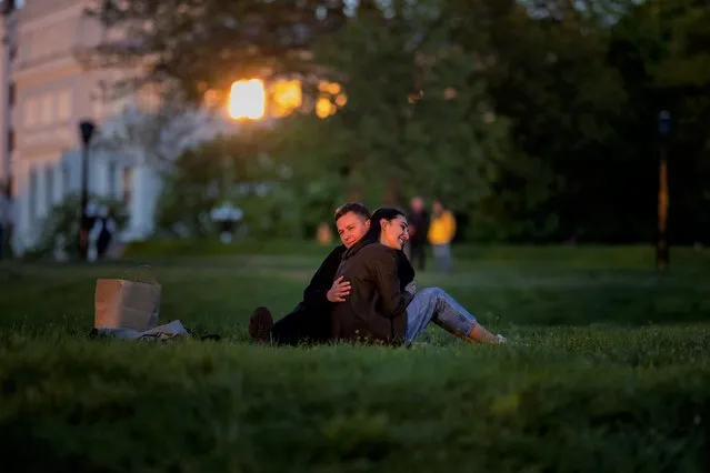 Stepan and Anastasia sit at a public park as the sun sets in Kyiv Ukraine on Tuesday, May 10, 2022. (Photo by Emilio Morenatti/AP Photo)