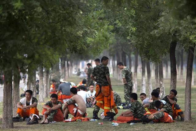 Chinese firefighters rest as they wait to be deployed near the site of an explosion in northeastern China's Tianjin municipality Saturday, August 15, 2015. (Photo by Ng Han Guan/AP Photo)